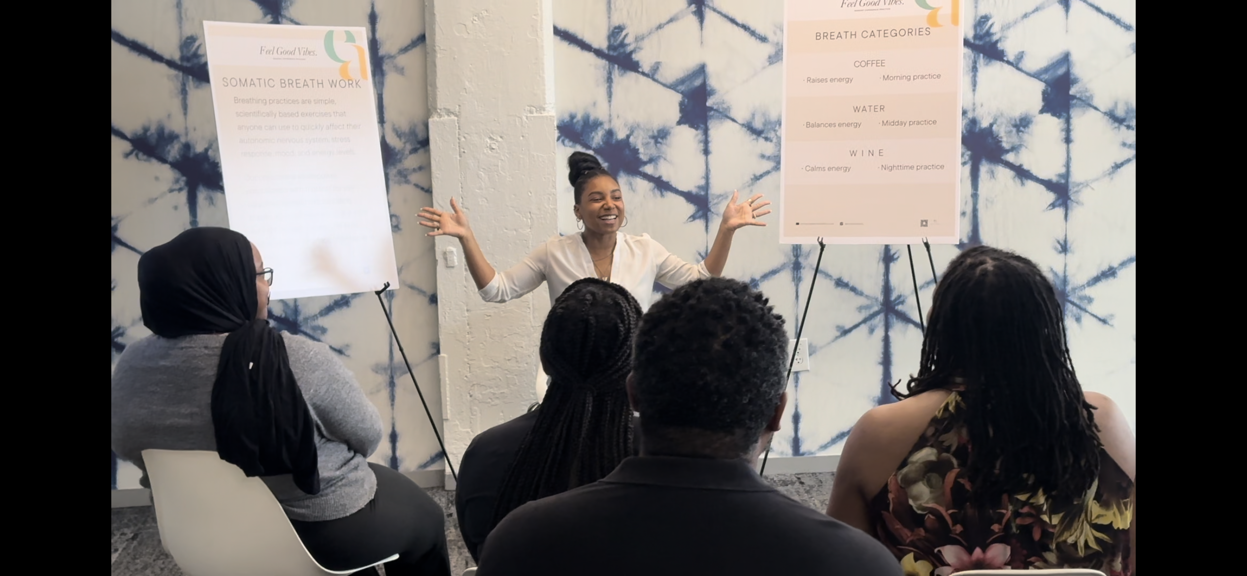 Ally facilitating a group wellness workshop, standing between two presentation boards